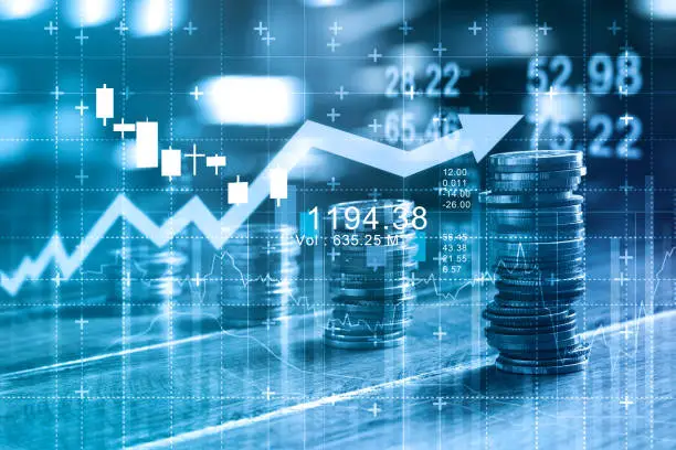 Photo of Finance and business concept. Investment graph and rows growth and of coins on table, blue color tone.