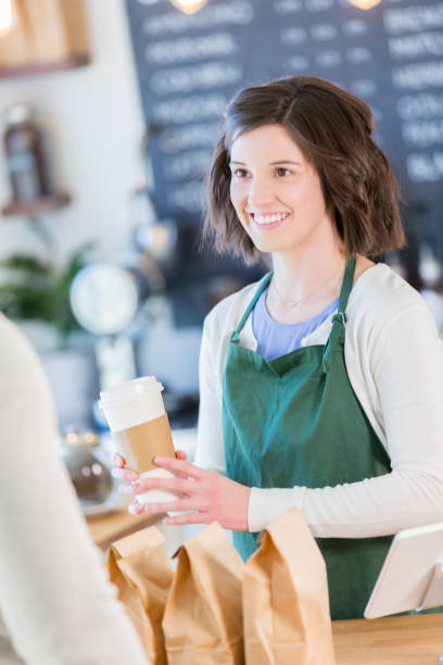 istock Beautiful female barista assists customer 927890036