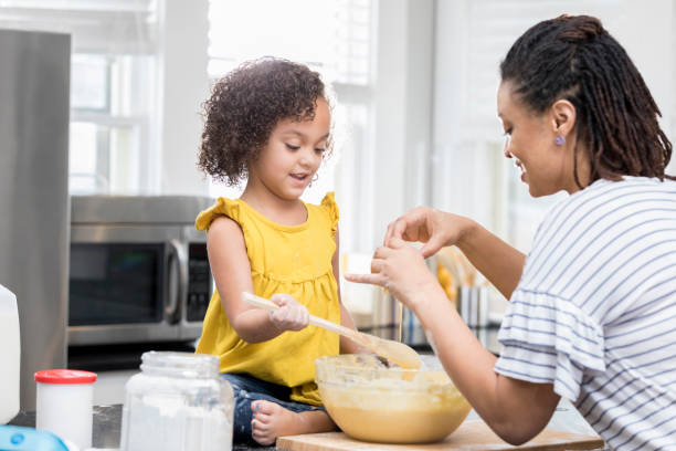 istock Little girl helps mom bake in kitchen 927892130
