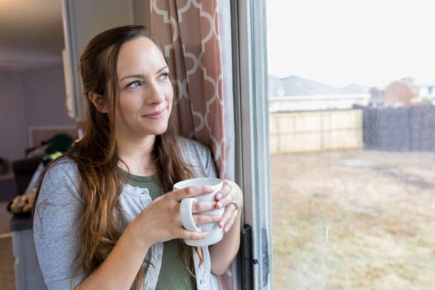 istock Confident mid adult woman day dreams while drinking coffee 927892210