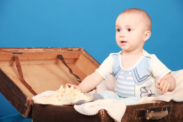 A little boy sits on a blue background in a chest in sailor suit