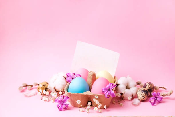 istock Traditional easter card template with pastel colors painted organic eggs in wicker basket with hay and decorative wildflowers. 927902676