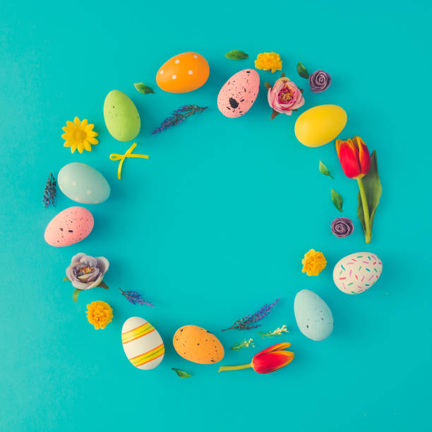 istock Creative Easter layout made of colorful eggs and flowers on blue background. Circle wreath flat lay concept. 927908468