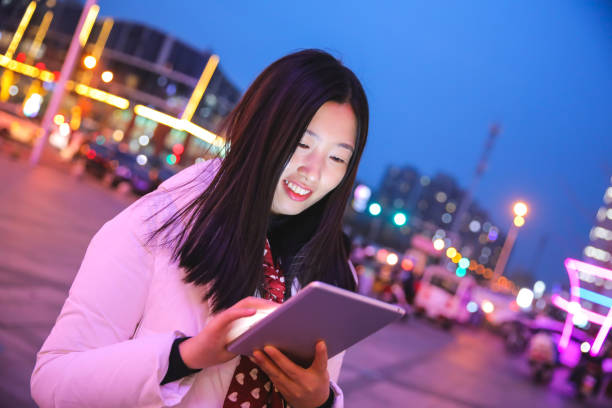 istock Young asian woman using digital tablet by night street 927924744