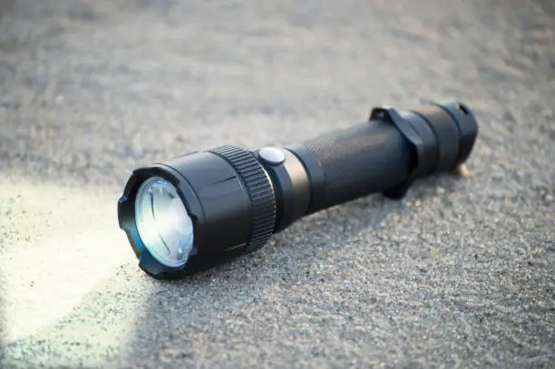 Photo of pocket LED flashlight lies on a sand