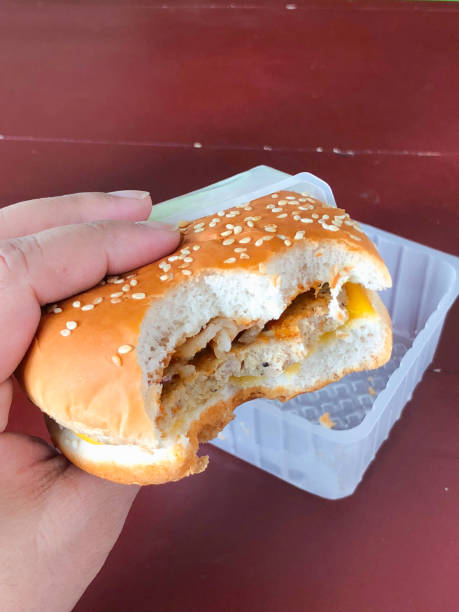 istock Young girl holding burger (front view) 927928084