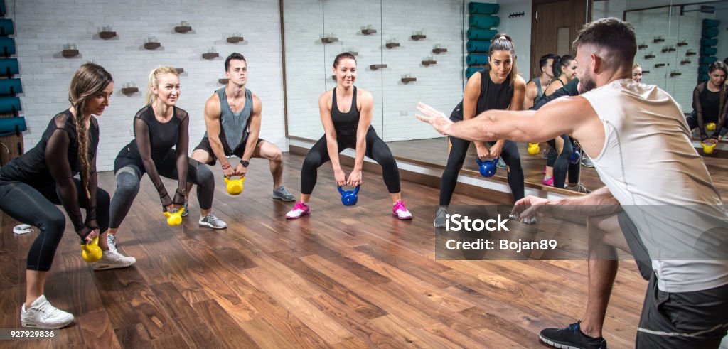 Vue panoramique du peuple sportif avec des poids de formation avec l’aide de leur entraîneur au club de santé. - Photo de Instructeur de fitness libre de droits