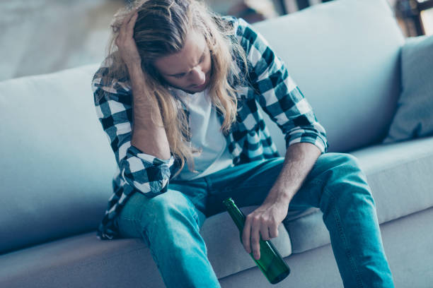 istock Frustrated single young guy is sitting on a sofa and  drinking alcohol bevegare because of having too much problems at work and with his girlfriend 927930690