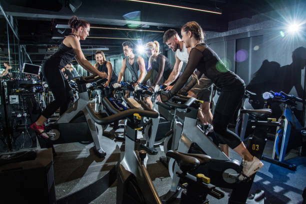 istock Group of sporty people training on exercise bikes during cycling class in gym. 927931884