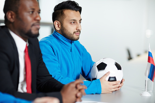 Member of football team and young politician listening attentively report of speaker at conference