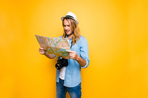 mentre l'uomo triste e deluso ha perso la strada per l'hotel e ora sta guardando la mappa e sta cercando di definire la strada per il punto di destinazione - tourist map men holding foto e immagini stock