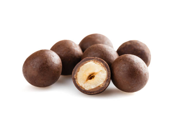 istock Heap of sugared hazelnuts dragees in chocolate isolated on white background 927940248