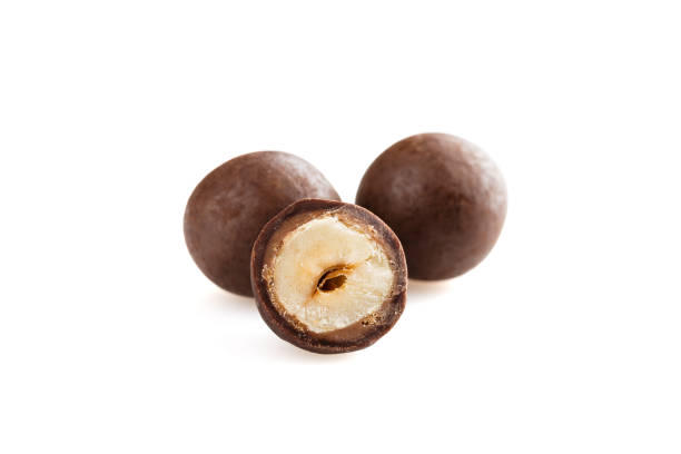 istock Heap of sugared hazelnuts dragees in chocolate isolated on white background 927940250