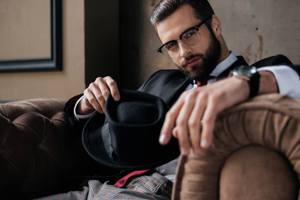 istock handsome stylish man in eyeglasses holding hat and looking at camera 927950478