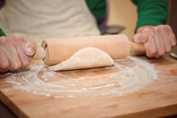 mains avec rouleau à pâtisserie et de la pâte à biscuits. mise au point sélective. - rolling dough pastry apron photos et images de collection