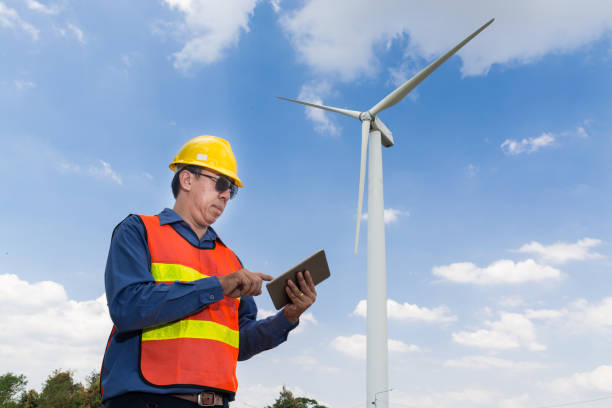 istock Electric Engineer use Tablet Device with Wind turbine power Generator Tower 927967020