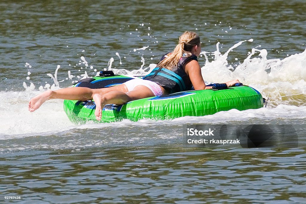Summer  Cool Down Blond woman in bathing suit on a rubber raft being towed through a river Inflatable Raft Stock Photo