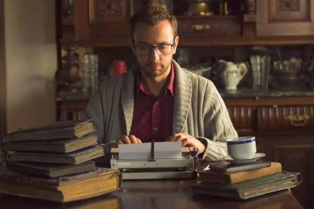 Photo of Young man writing on old typewriter.