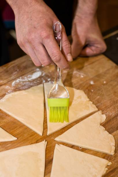 istock Brushing with a brush and egg on a dough.Selective focus. 927975740
