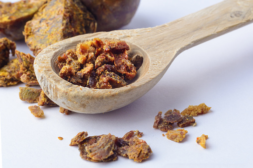 Propolis granules in a wooden spoon. Bee glue. Bee products. Apitherapy. Apiculture