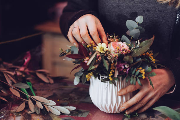 Modern florist working with flowers in workshop - with detail on hands stock photo