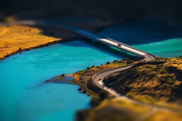 Two cars crossing blue river on the bridge. Chile. Tilt shift effect applied