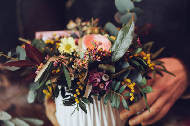 Modern florist working with flowers in workshop - with detail on hands stock photo