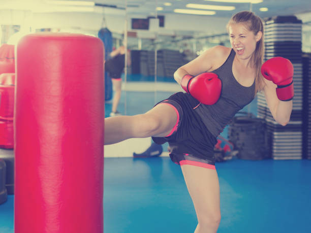 istock Active woman practicing with punching bag in box gym 927995382