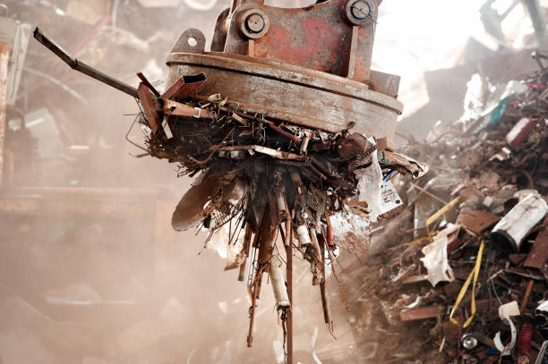 Big magnet in junk yard magnet cranes are used in the recycling industry to remove iron scraps from  junkyard to recycle.The metal waste can  reused many times  ,decreased air pollution and greenhouse gases junkyard photos stock pictures, royalty-free photos & images