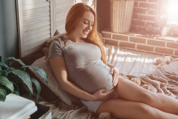 istock Future mom laying on the bed resting while touching her belly 928002858