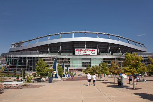 Visitors in shorts and t-shits walk towards the entrance of Sports Authority Field at Mile High to watch a free Broncos scrimmage game in the summertime in Denver.