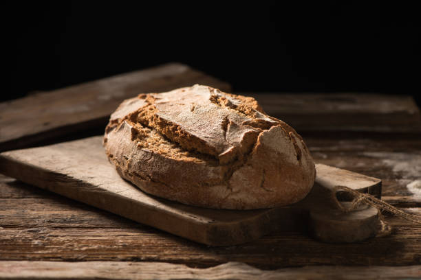 istock Freshly baked bread on wooden table on dark background 928008932
