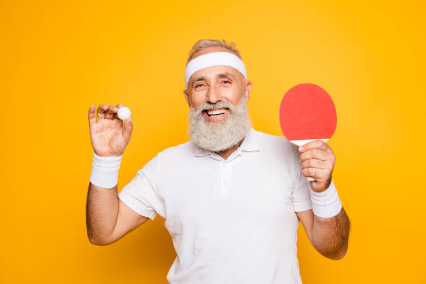 istock Competetive emotional cool active goofy comic grey haired grandpa with humor grimace and beaming grin, with table tennis equipment. Healthcare, weight loss, bodycare lifestyle 928012558