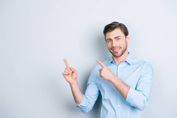 istock Advertisement concept. Successful caucasion man with beaming smile on grey background  is pointing on empty copy space with his fingers 928020288