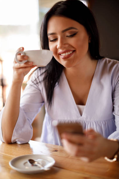 istock Young woman text messaging on mobile phone at a cafe 928024378