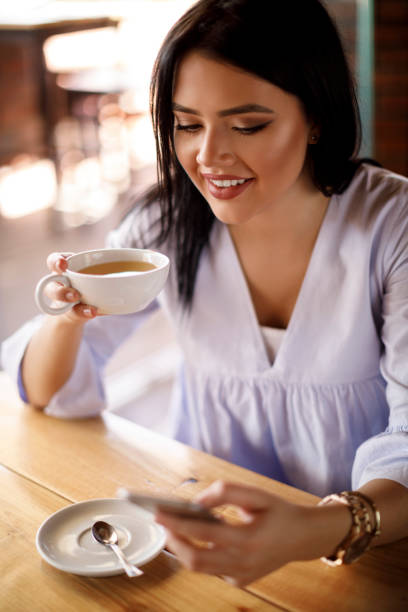 istock Young woman text messaging on mobile phone at a cafe 928024494