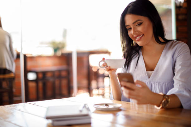 istock Beautiful young woman drinking tea and text messaging on mobile phone 928024614