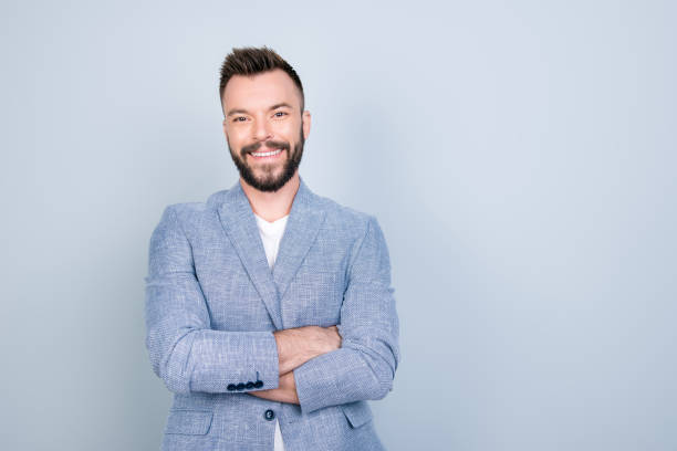 Close up portrait of young successful brunet stock market broker guy on the pure light blue background, he is smiling, wearing smart casual, stands with crossed arms Close up portrait of young successful brunet stock market broker guy on the pure light blue background, he is smiling, wearing smart casual, stands with crossed arms business person one man only blue standing stock pictures, royalty-free photos & images