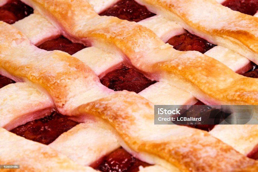 Macro photograph of a lattice pastry crust red cherry pie Macro photograph of a lattice crust freshly baked homemade cherry pie. The lattice forms a nice pattern for a food background. The red cherries are ripe and juicy. The crust has a uniform crisp look to it. Backgrounds Stock Photo