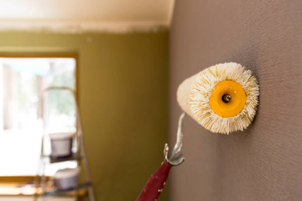 istock Roller for painting against grey wall. Ladder and paint bucket on background 928040182