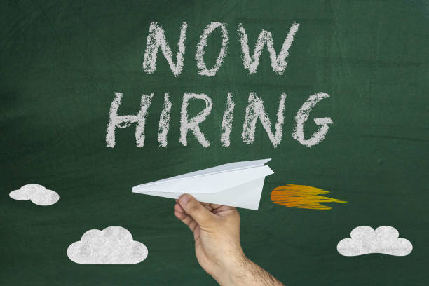 istock HR concept. Hand with plane and text: Now hiring. 928044036