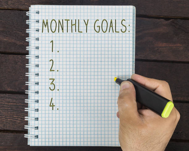 istock male hand is writing monthly goals on a notepad 928044482