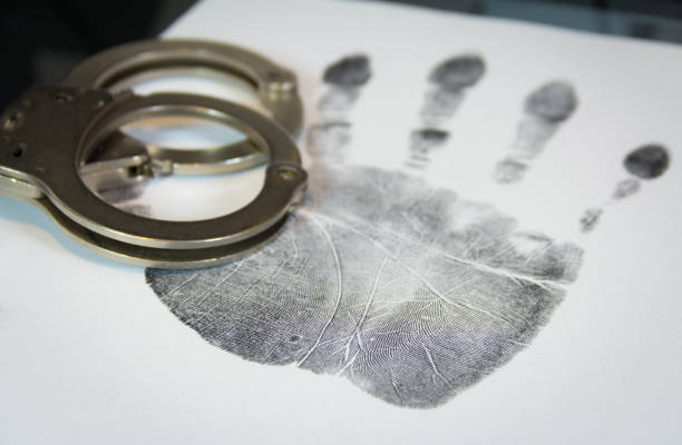 istock Handcuffs and a palm print on white paper 928048014