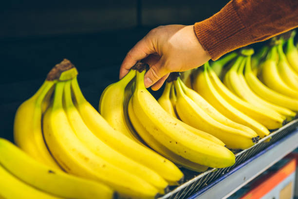mans hand take bananas from shelf of store. healthy food. shopping concept - department store imagens e fotografias de stock