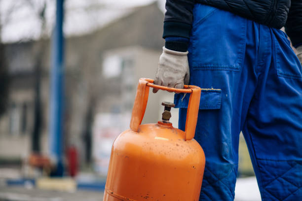 man carrying lpg gas bottle at gas station - botija de gas imagens e fotografias de stock