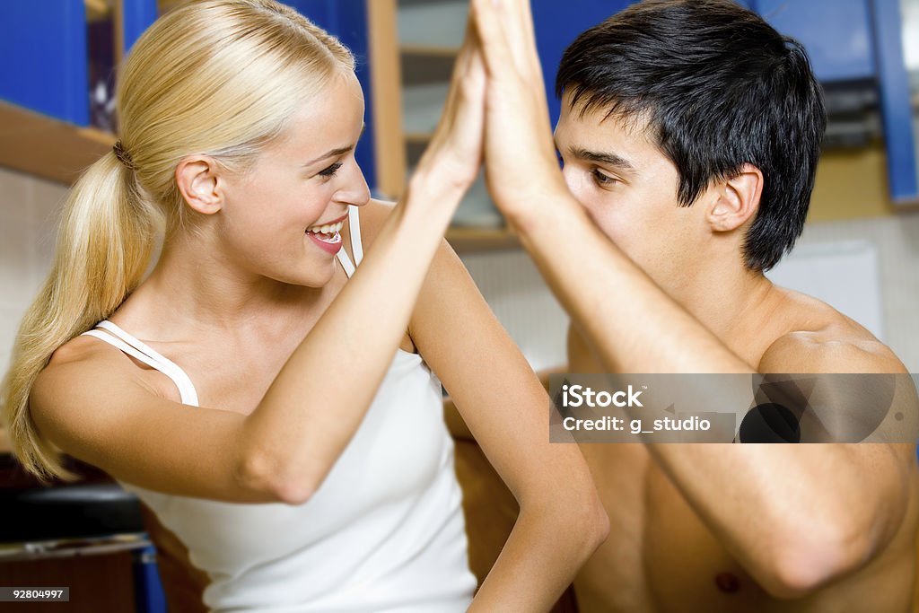 Giovane felice sorridente coppia romantica gesti di una vittoria, a casa - Foto stock royalty-free di Abbracciare una persona