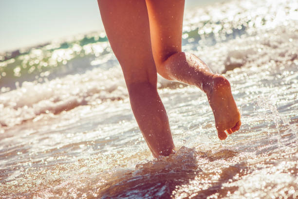 A young woman running on the beach. She enjoy exercising on the sea in sunset.