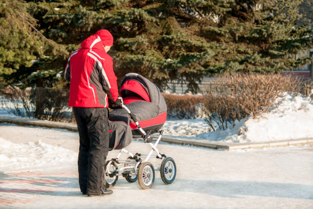istock Man with baby stroller walks through the winter park 928062514