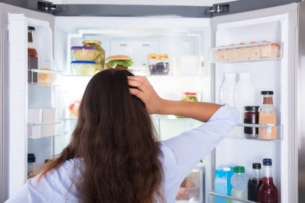 istock Confused Woman Looking In Open Refrigerator 928066088