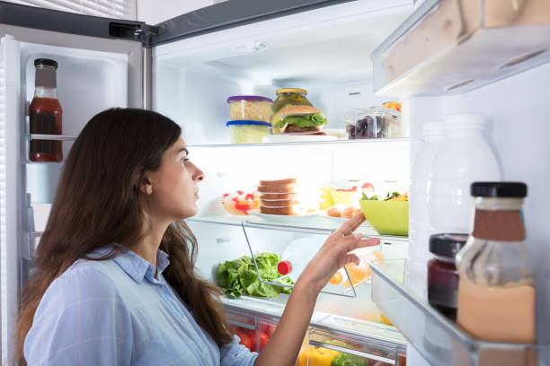 istock Young Woman Looking At Food In Refrigerator 928066106